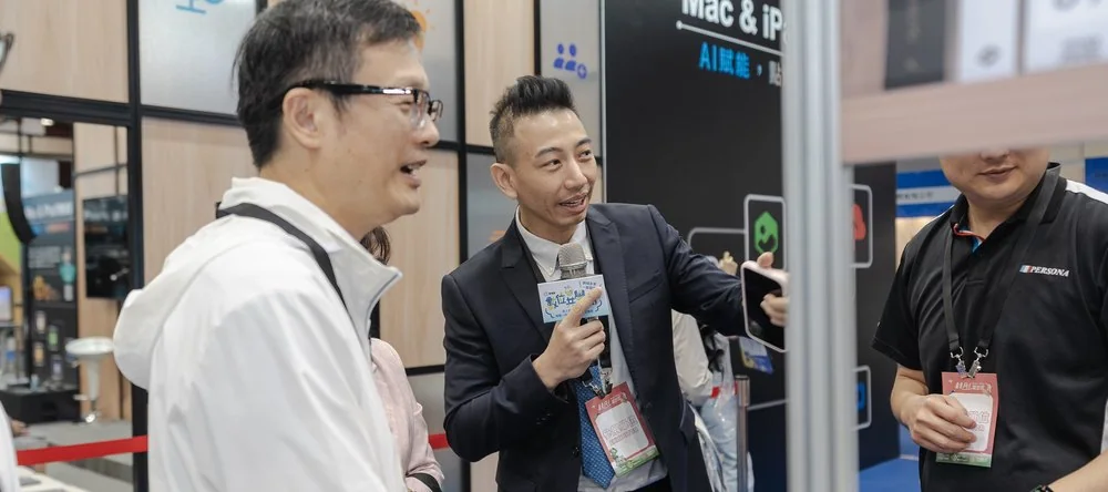 2025 現場實景：解說員拿著麥克風為參觀者示範平板教學應用