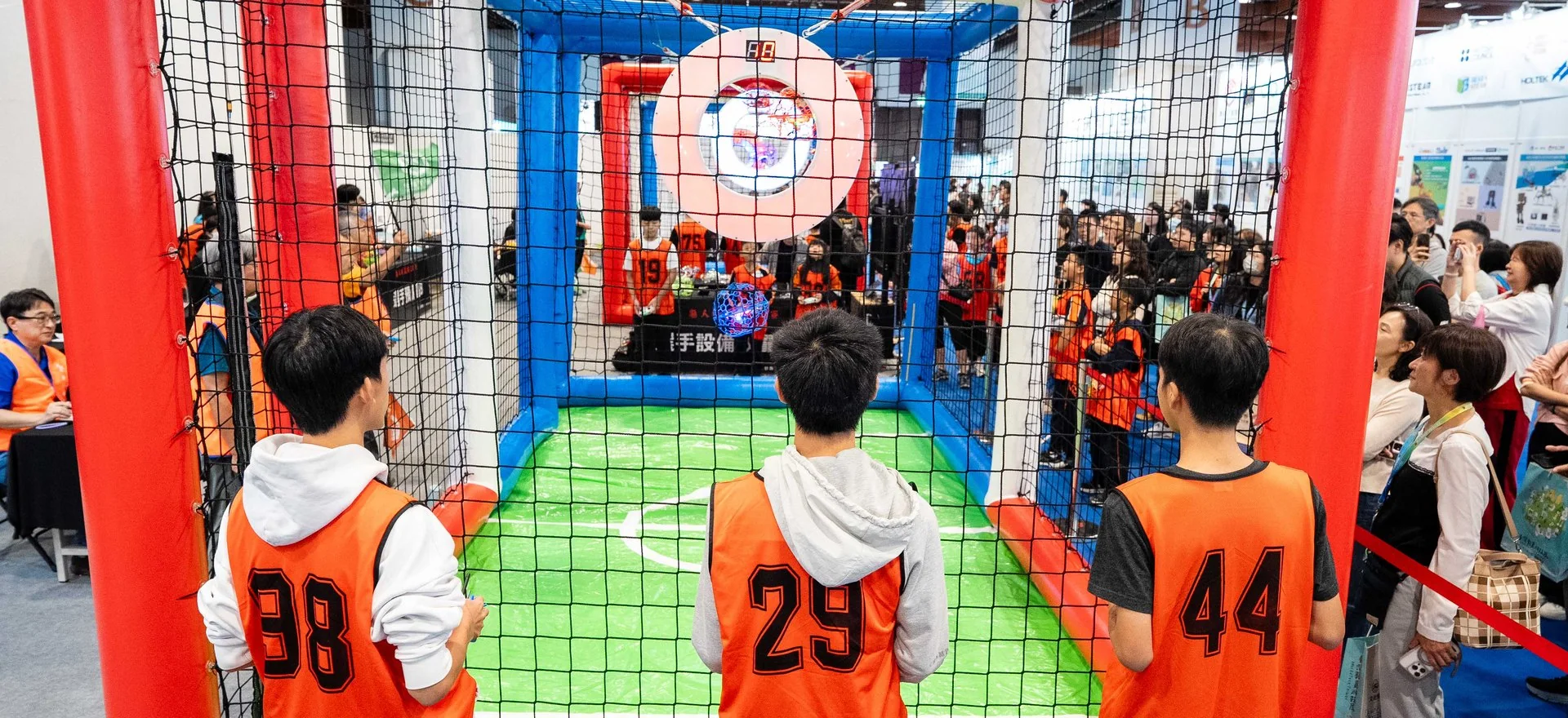 2025 現場實景：無人機足球選手在球場網外操控，觀眾圍觀
