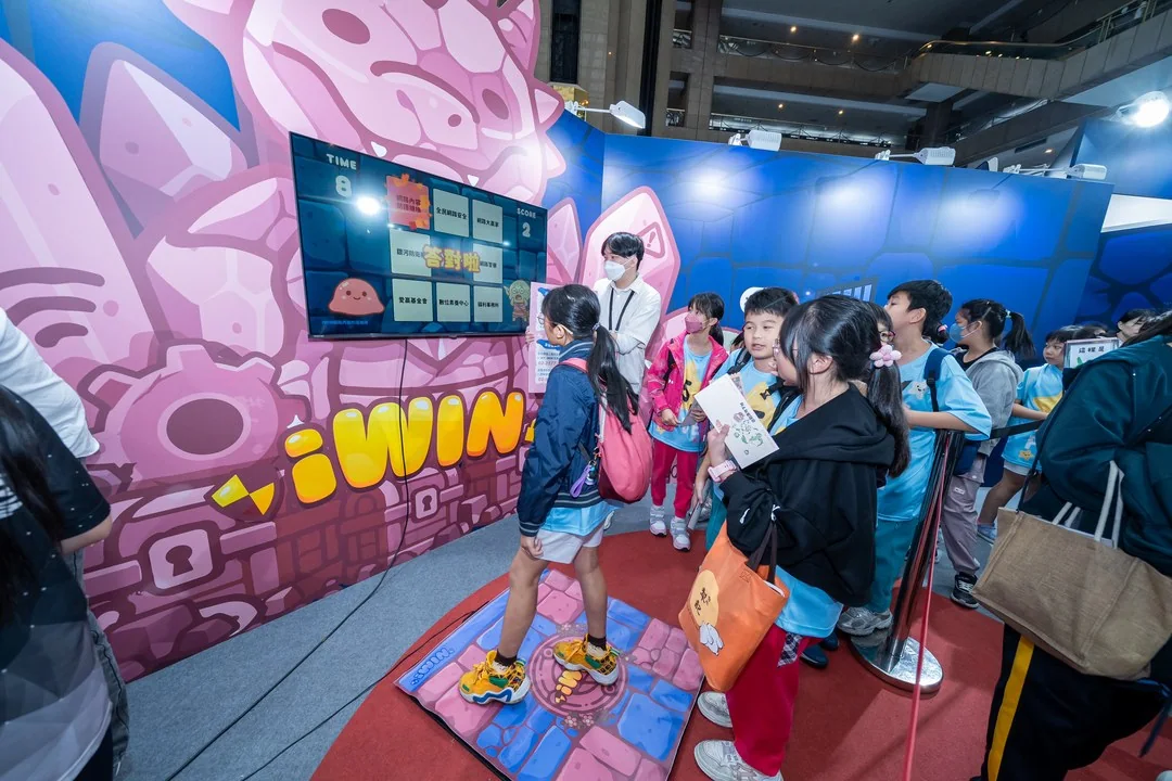2025 現場實景：iWIN 展區，學生在互動闖關牆前體驗網安遊戲