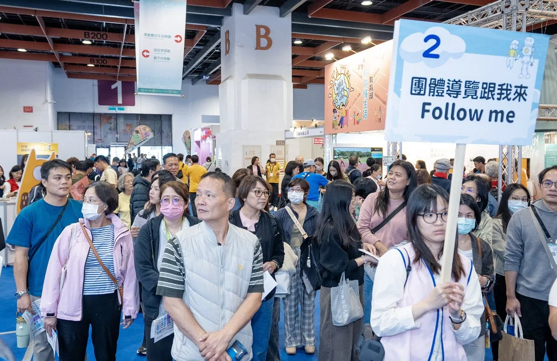 2025 現場實景：導覽人員舉「團體導覽跟我來」牌帶領參觀民眾