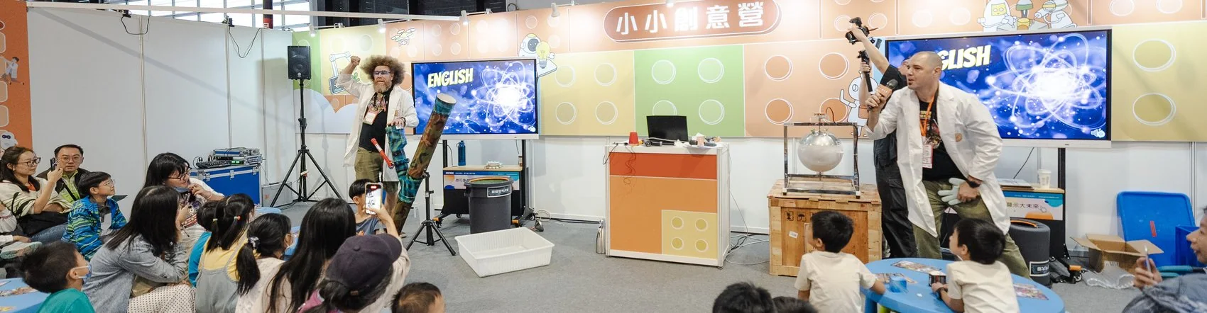 2025 現場實景：親子共學園小小創意營，親子家庭在台下觀看科學實驗秀